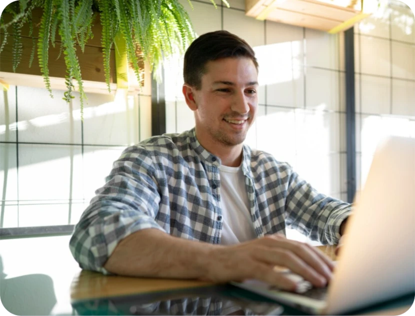 joven sonriendo frente a una laptop