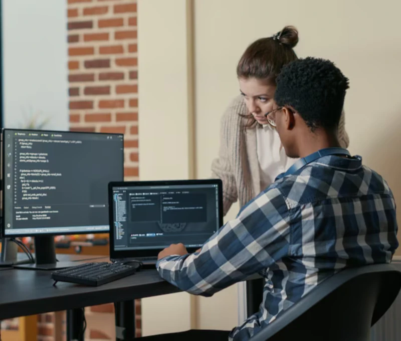 Hombre y mujer verificando programación en laptop y pc