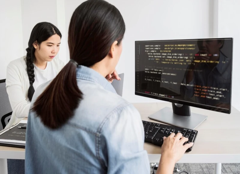 Mujeres programando en computadoras y laptop