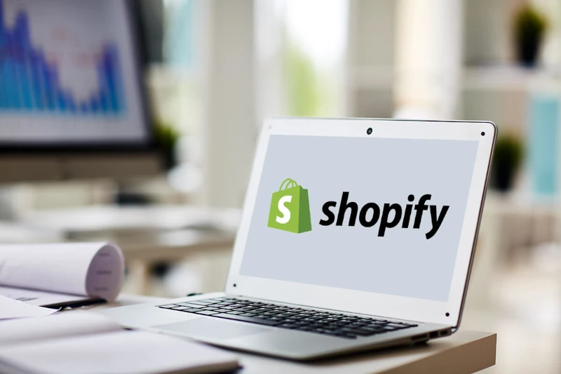 Laptop sobre mesa con logo de Shopify