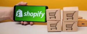 Teléfono con logo de Shopify al lado de cajas